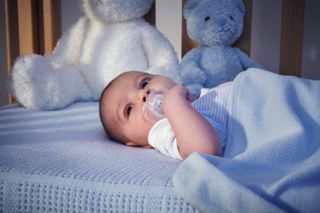 Baby boy and teddy bears in crib at night