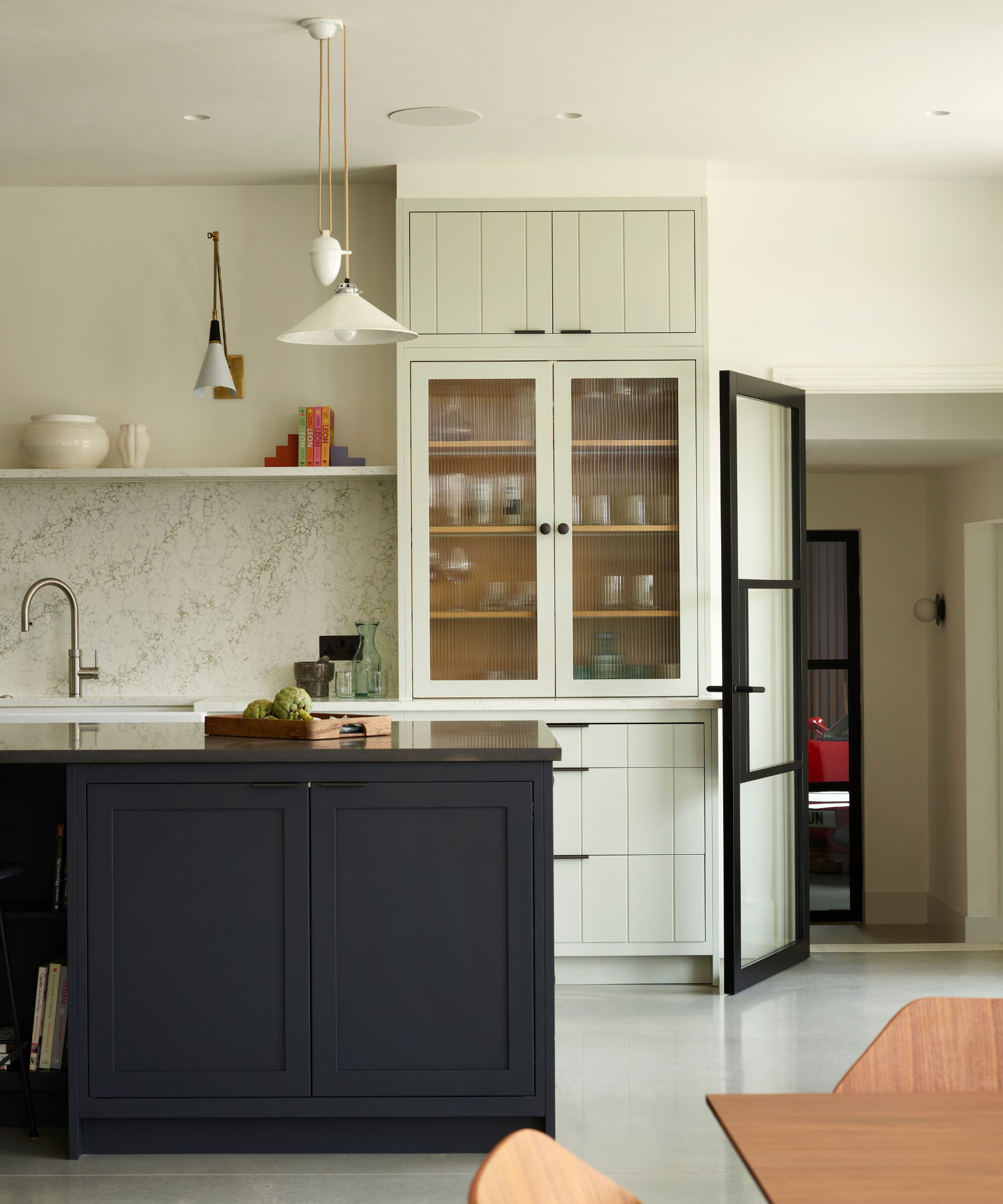 modern kitchen with white walls, pale green cabinets and navy blue kitchen island