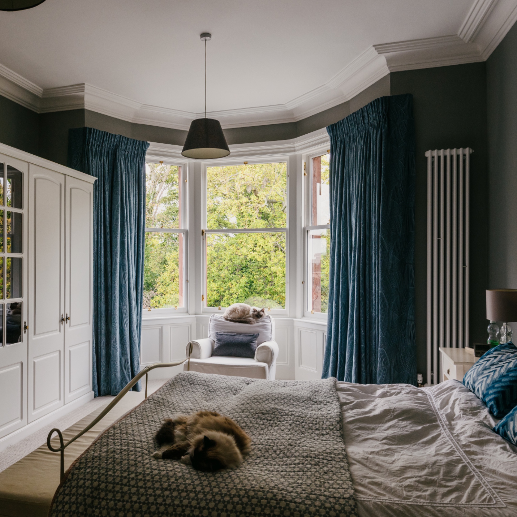 bedroom with blue curtains, bay window, built in storage