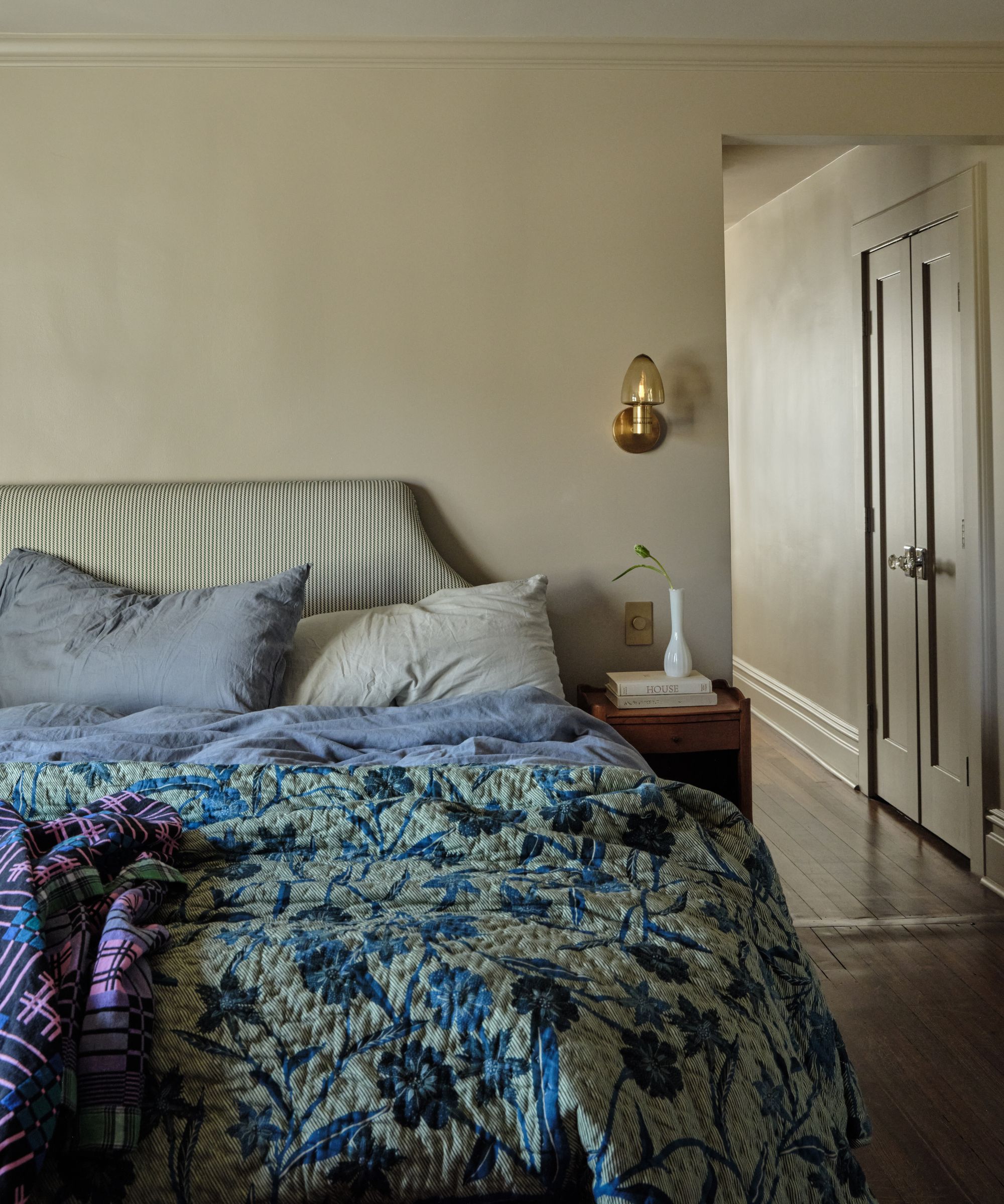 a soft green primary bedroom with a striped headboard and blue and green bedding