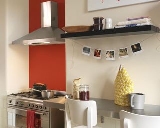 A white kitchen with red paint decor used to color block the hob area
