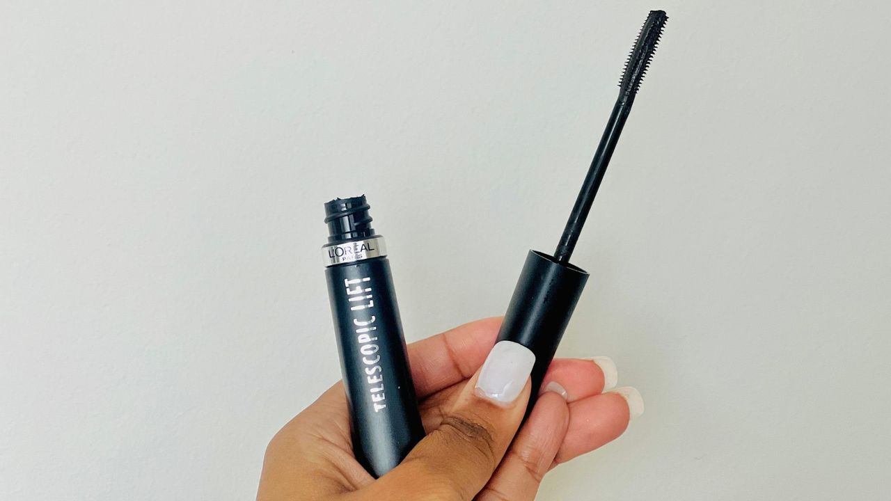 A person holding an opened L'Oreal Telescopic Lift mascara, showing the wand and brush shape, for the best L'Oreal mascara.
