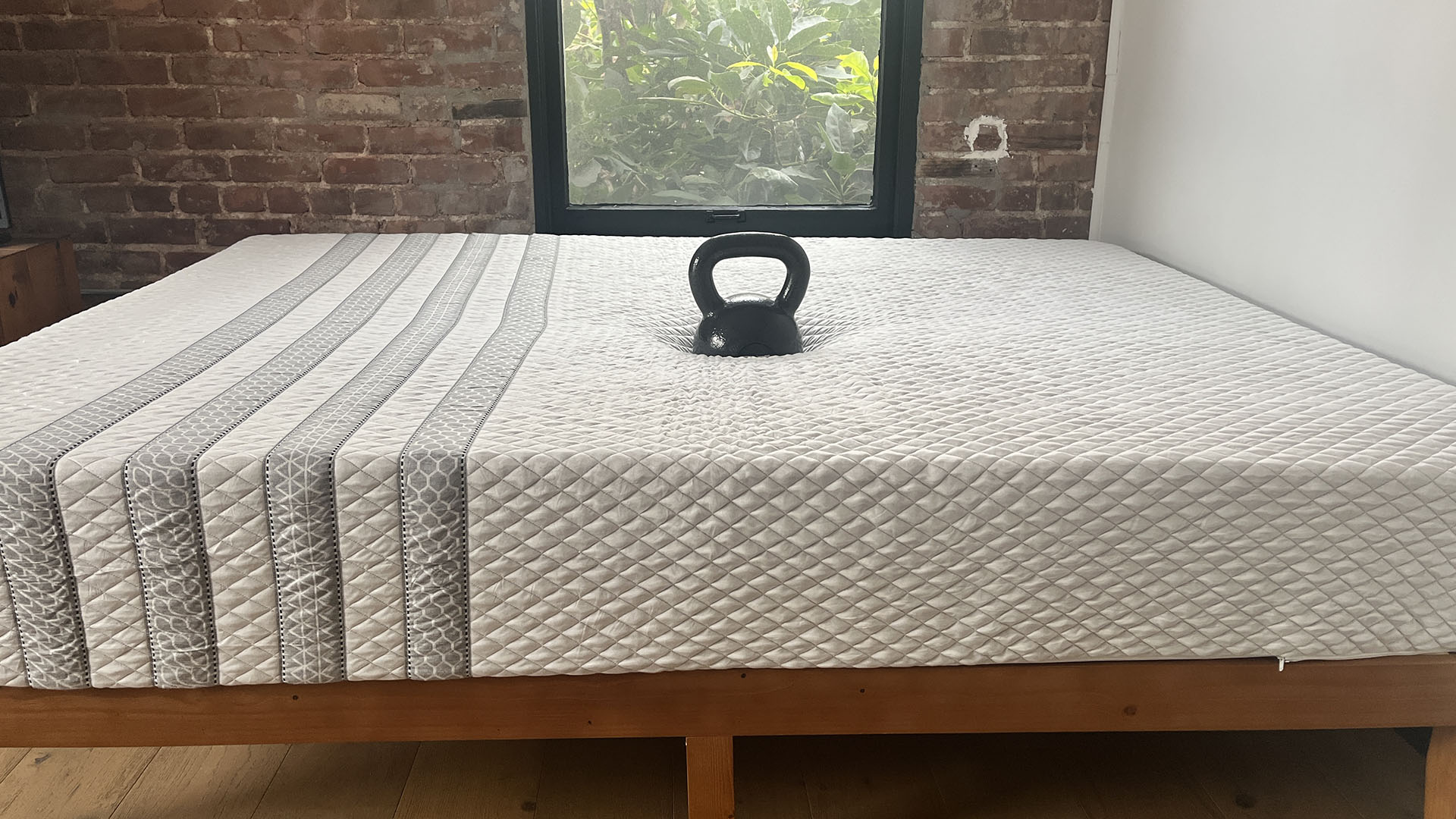 Leesa Sapira Hybrid matress on a wooden bedframe in a red brick bedroom