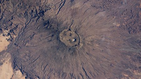 A satellite photo of a volcano with a bright white patch at its summit