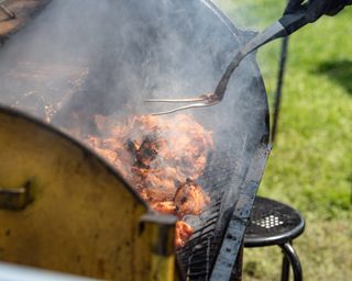 Jerk chicken cooking in a traditional oil drum barbecue