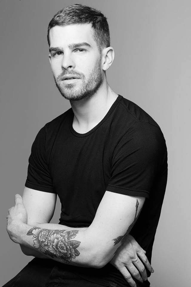a black and white photo of a white man with a beard and tattoos