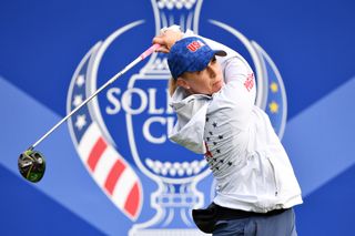 Morgan Pressel hits a tee shot with a driver in front of a Solheim Cup board