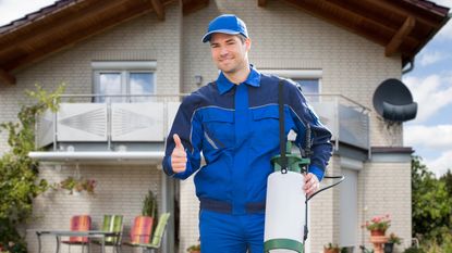 An exterminator smiles outside a home.