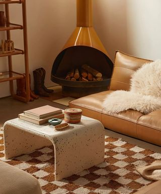 Living room with brown checkered rug, leather sofa, and gold fireplace