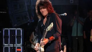 Tommy Thayer performs onstage holding a white Gibson Les Paul