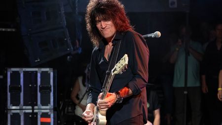 Tommy Thayer performs onstage holding a white Gibson Les Paul