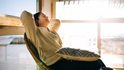 Woman leaning back in chair, sunshine coming through window in winter