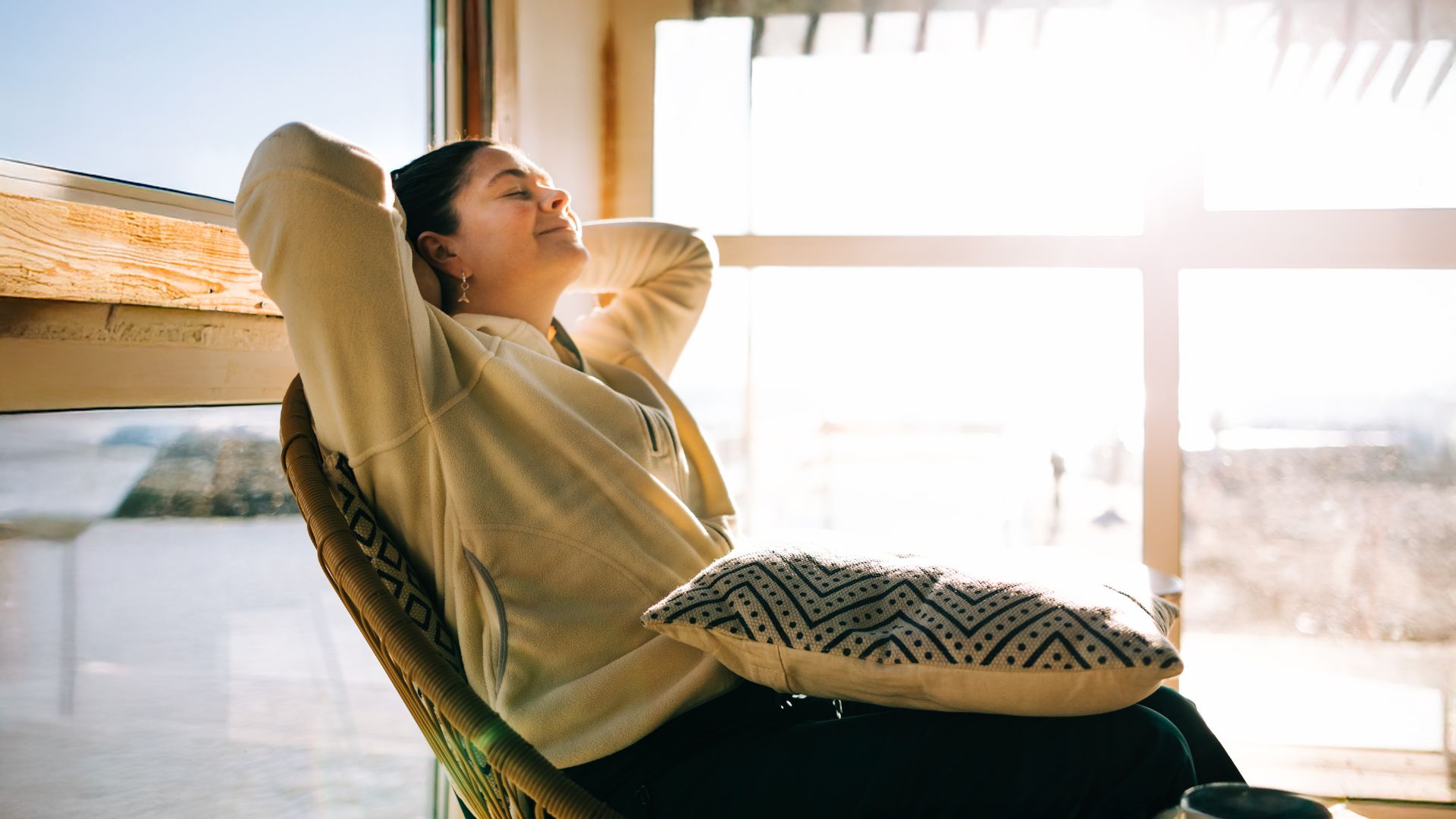 Woman leaning back in chair, sunshine coming through window in winter
