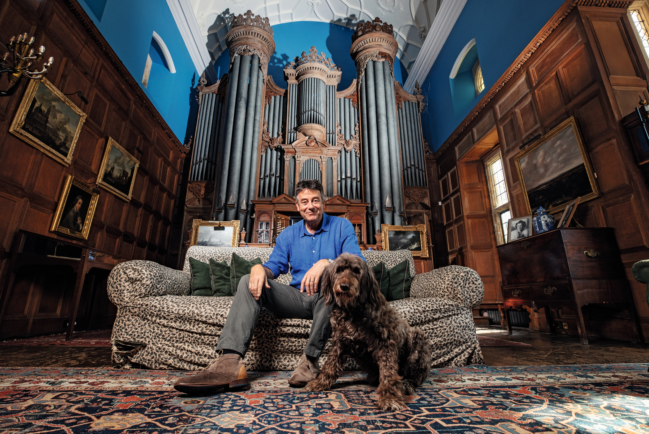 Gus Christie sits with his large dog in front of the organ at Glyndebourne.