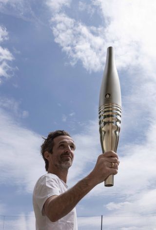 Mathieu Lehanneur holds up the Paris 2024 Olympic torch
