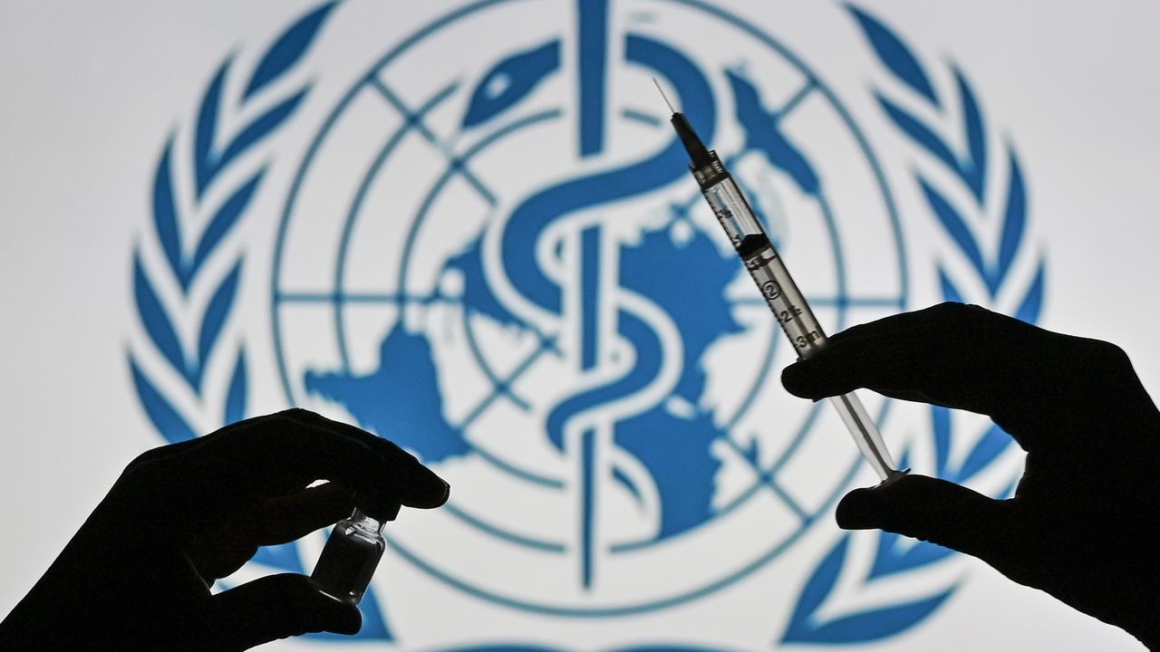 A syringe and vial held in front of the World Health Organisation logo