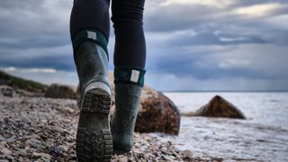 Close up of a walker on a pebble beach wearing wellies