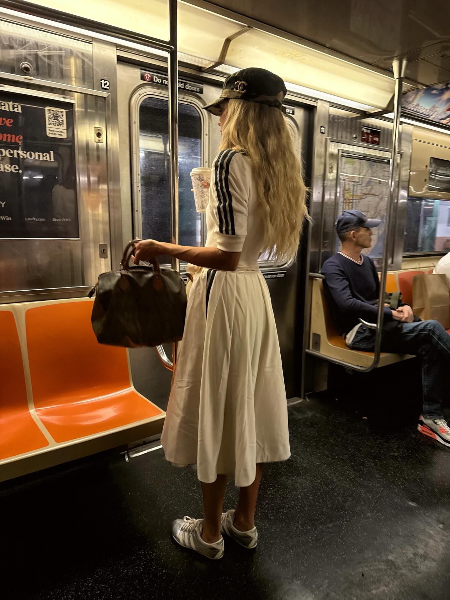 An image of @emilisindlev wearing satin trainers with a white skirt and white shirt while out in New York.