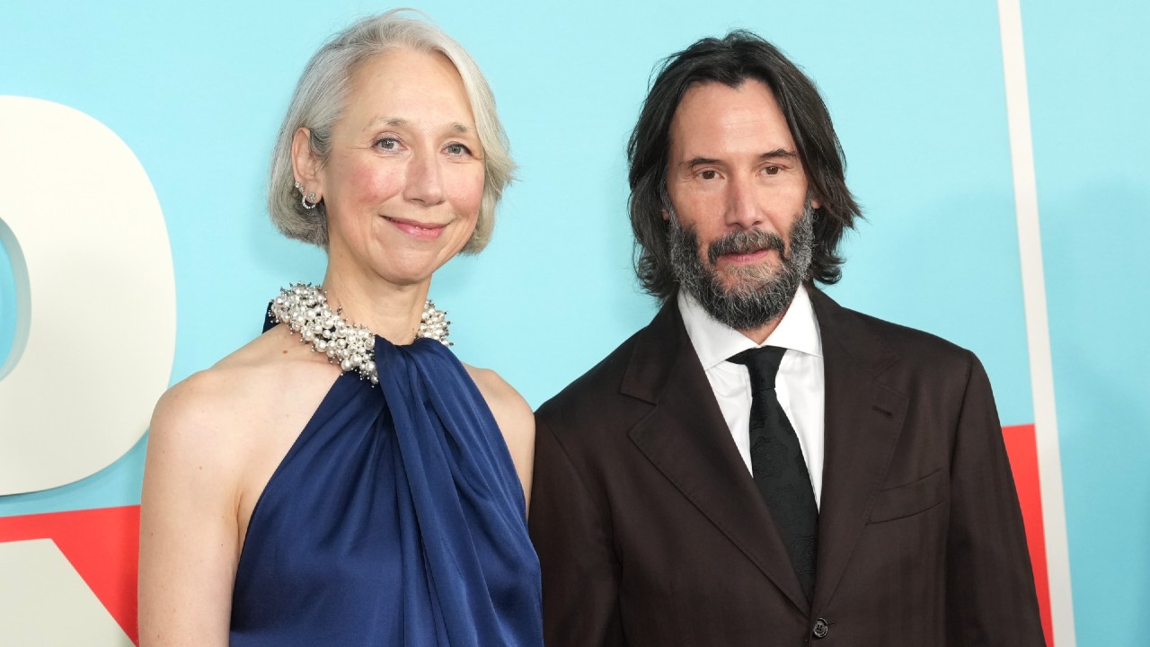 From left to right: Alexandra Grant and Keanu Reeves standing together and smiling at the Good Fortune special screening in New York City on October 13, 2025.