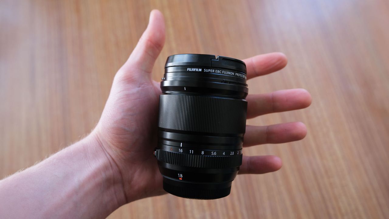 An open hand with the Fujifilm XF 18mm f/1.4 lens in the palm