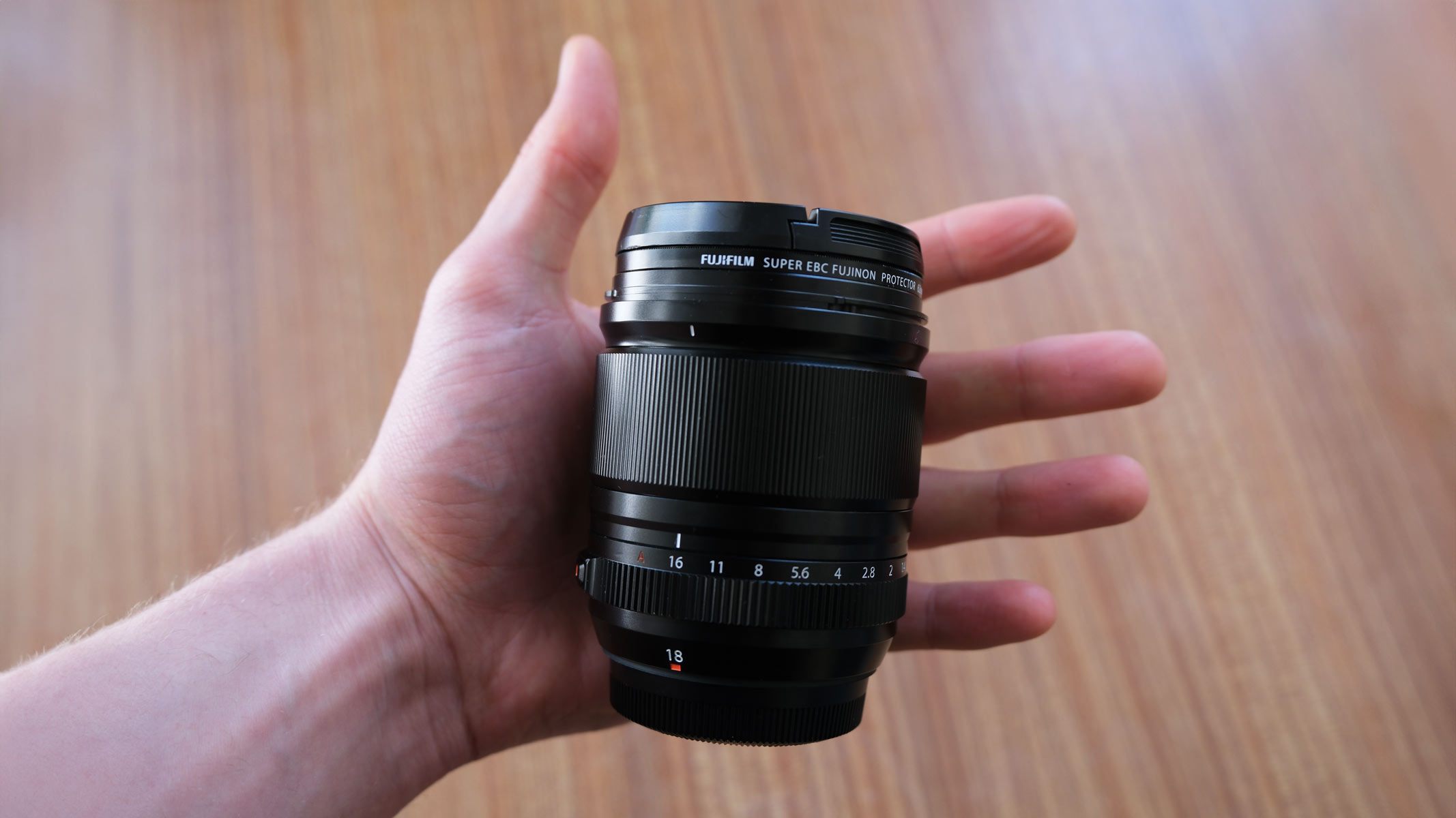 An open hand with the Fujifilm XF 18mm f/1.4 lens in the palm