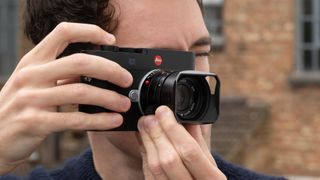 Leica M EV1 digital camera with lens attached held up to a person's face