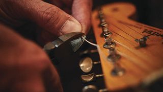 A man changing the strings on a Fender Stratocaster