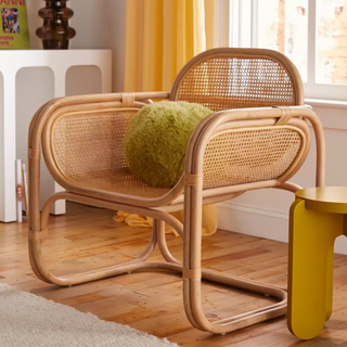 A lounge chair made of cane and rattan in a living room with yellow decor