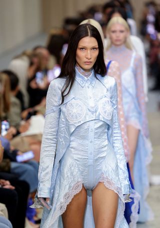 Bella Hadid berjalan di runway Burberry dengan mengenakan pakaian berwarna biru muda
