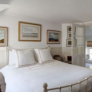 guest bedroom with white wall and frame on wall with cushions on bed