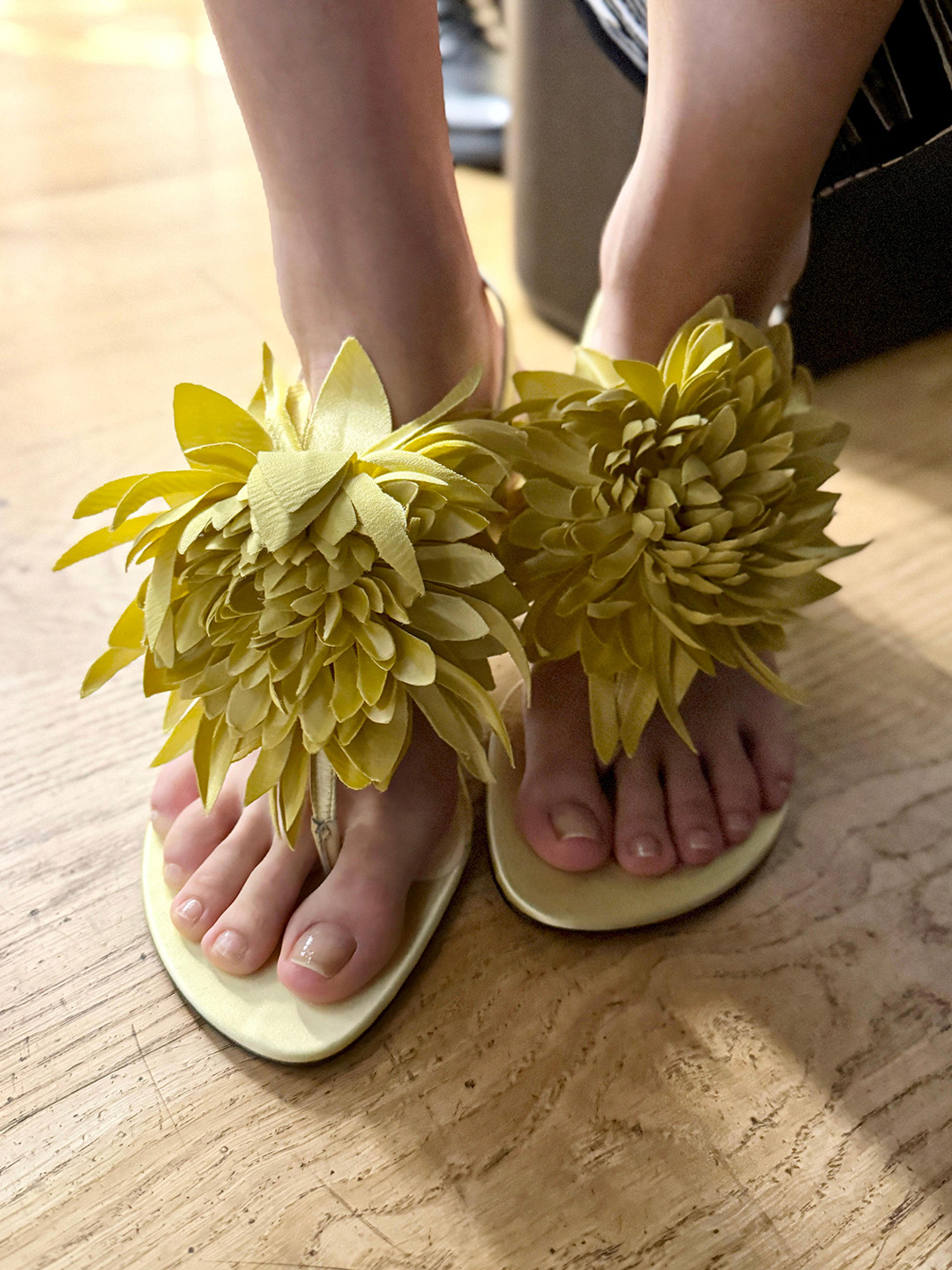 Photo of feet in yellow sandals with a clear, glass pedicure