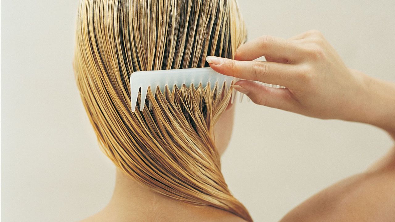 Blonde woman running a comb through her wet hair