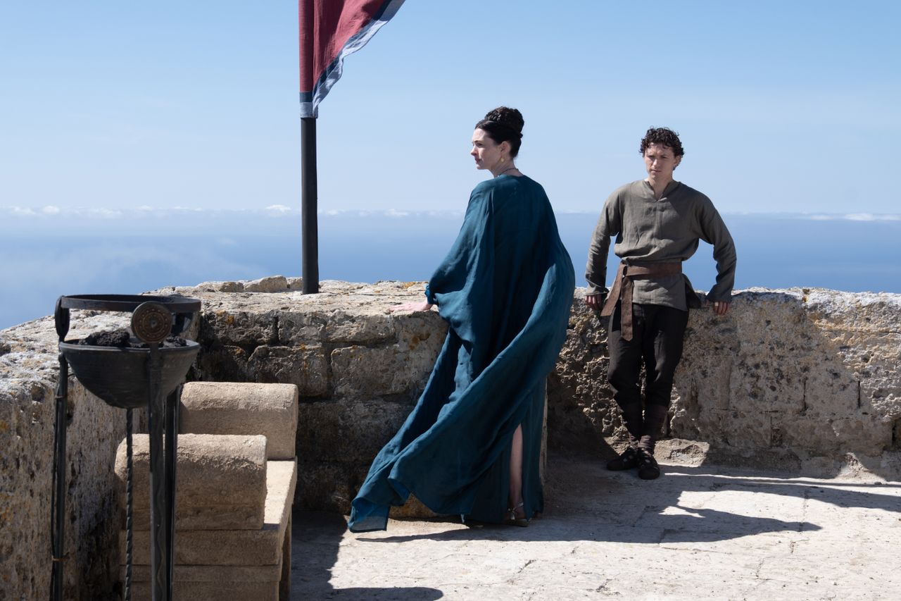 A series of set shots of actors dressed in period clothing, filming along rugged coasts, tranquil sandy beaches, and rocky fortresses.