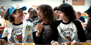 Dustin, Eddie and Mike talking in the Hellfire Club T-shirts, featuring one of the best Stranger Things fonts