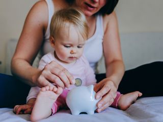 Mother and baby girl putting coins into a piggy bank