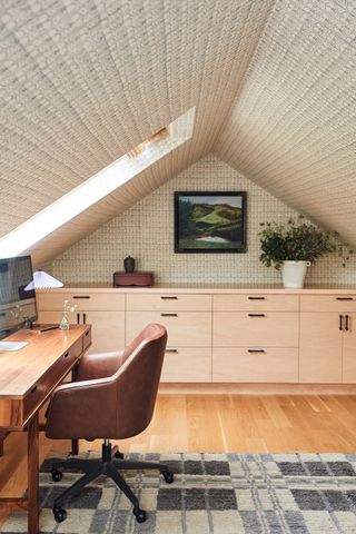 desk and office chair in loft room with fabric covered walls and ceiling and storage unit with geometric rug