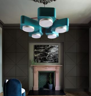 A living room with dark gray walls and a turquoise lighting piece