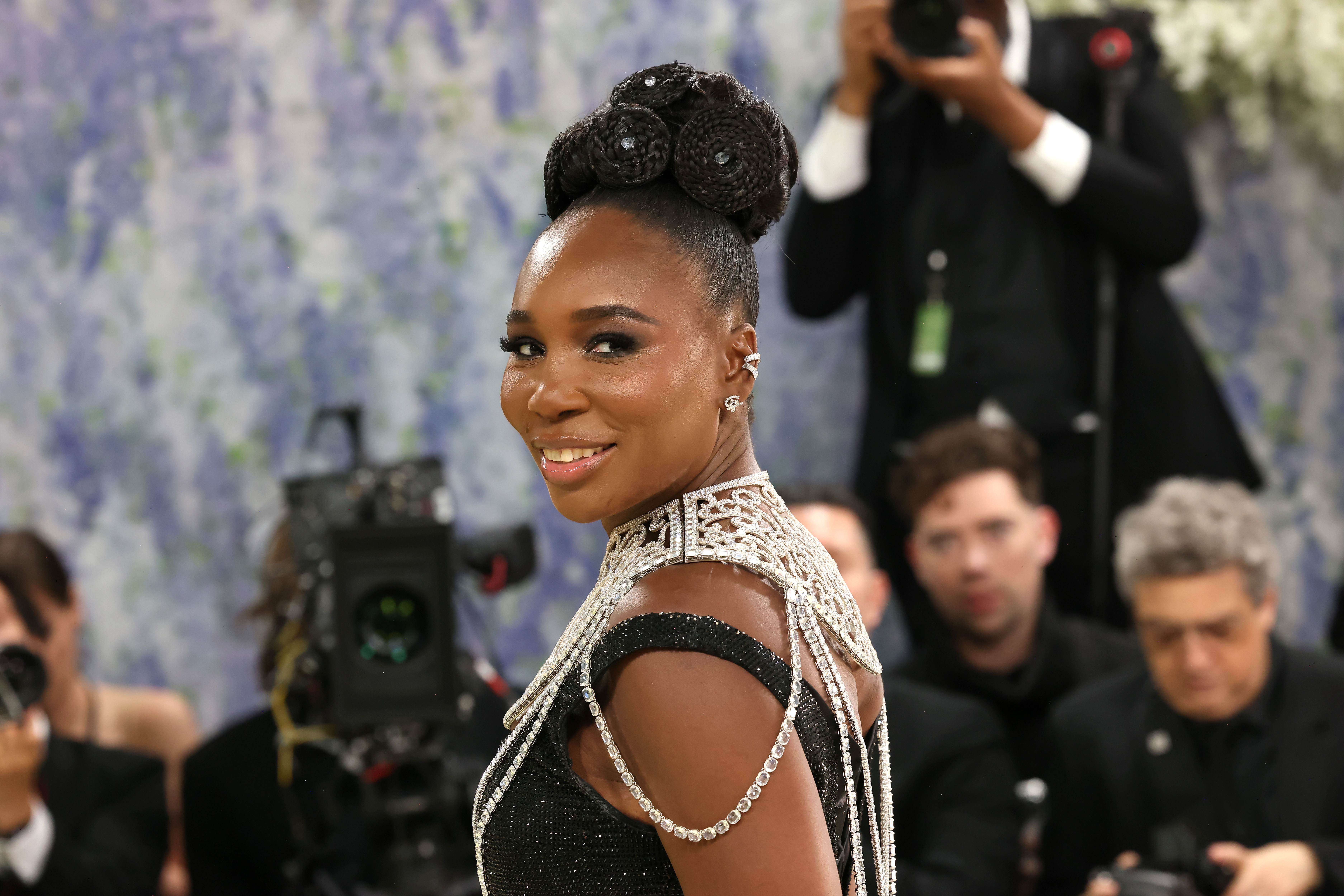 a woman in a black and diamond dress with a gem-encrusted updo and dark eye makeup