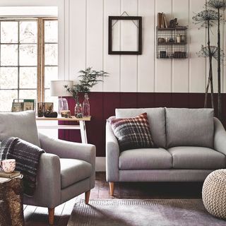 A living room with white and red wall panelling with a grey sofa and armchair