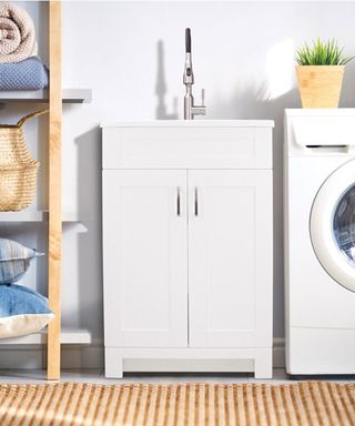 transolid cabinet laundry sink in a laundry room with washing machine and shelving unit
