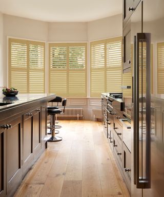 modern kitchen with dark cabinetry, light oak floors and soft yellow window shutters