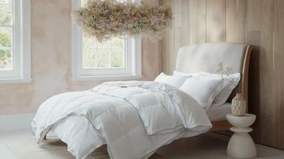 White duvet tog on a bed beneath a hanging flower arrangement.