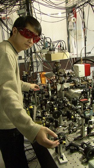 James Chin-wen Chou of NIST stands with a quantum logic clock based on vibrations of a single aluminum ion trapped inside a metal cylinder.