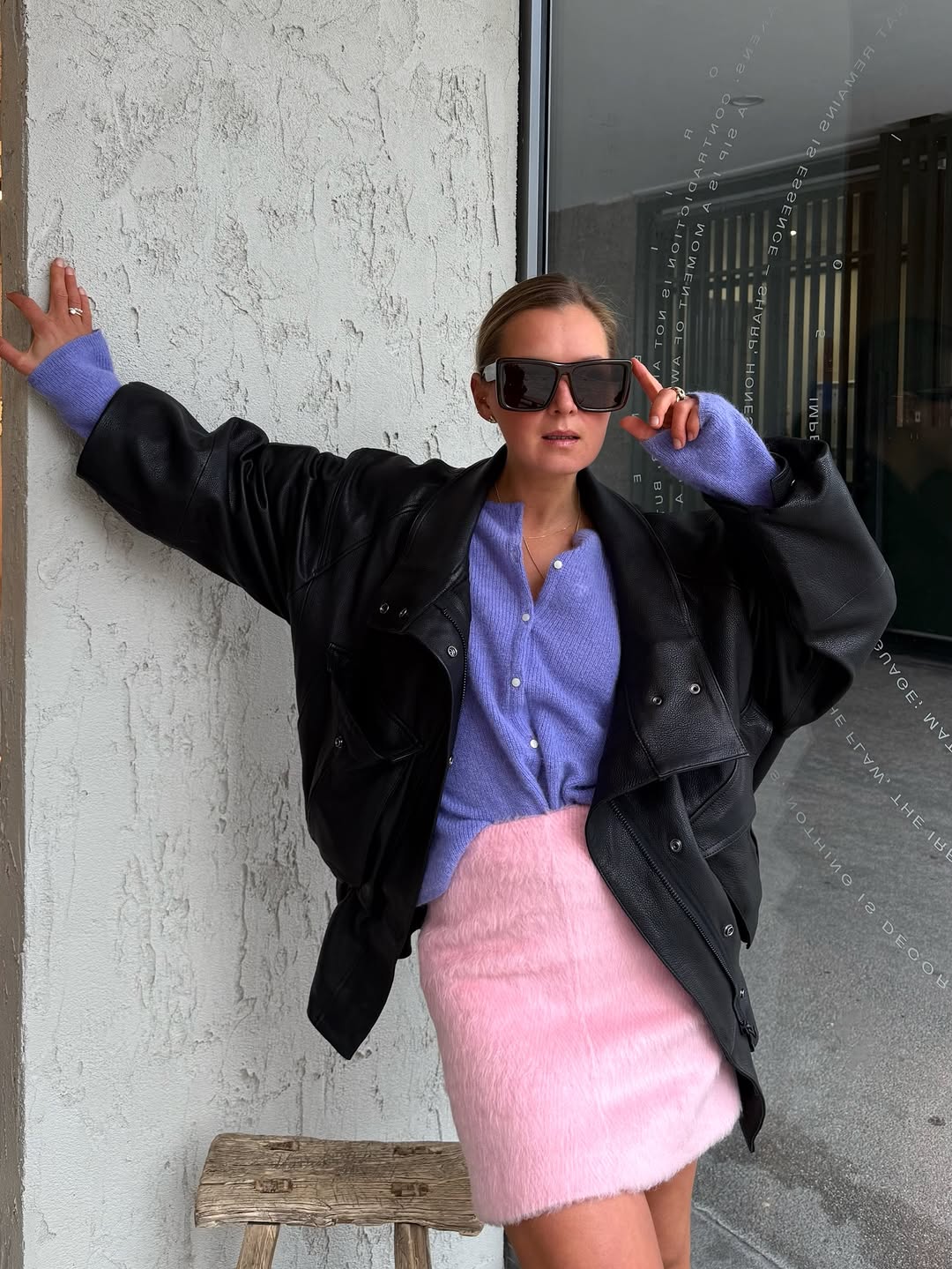 An image of a woman wearing a pink miniskirt and purple cardigan, one of the biggest 2026 spring color pairings.