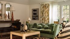 modern living room with green sofa, yellow lacquer coffee table, console with mirrors, table lamps, decor, artwork on walls, floral pattern curtains with double curtain rod with sheer curtains behind