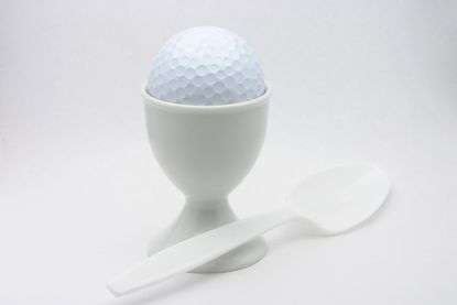 Breakfast ball image of a golf ball perched in an egg cup 