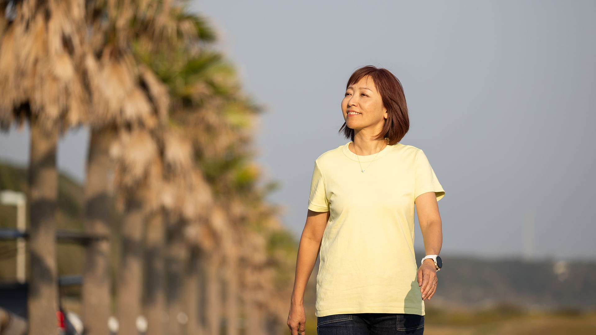 A woman walks along the boardwalk near the beach where she is traveling.