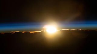 the sun rises over the horizon as seen from space