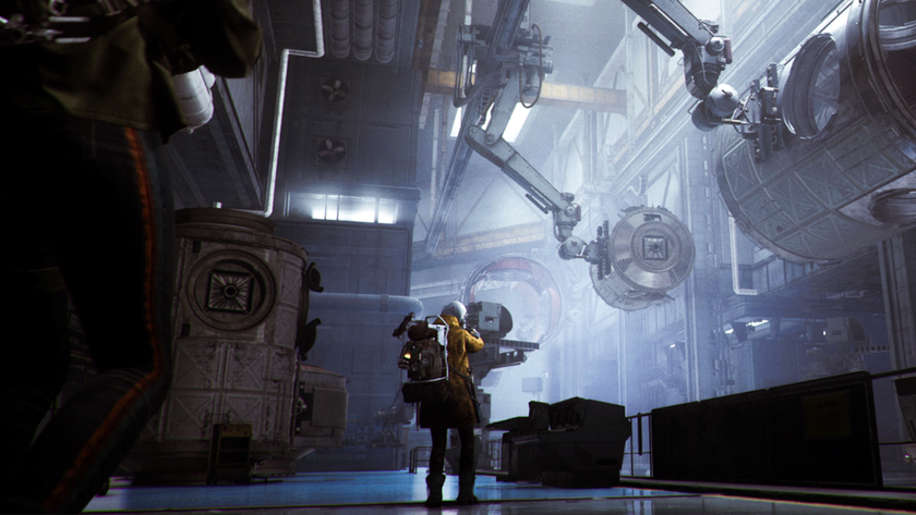 A Raider in yellow walks down a futuristic hallway in an assembly plant