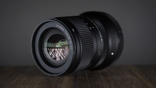 Sigma 18-50mm f/2.8 DC DN | C in Canon RF mount, on a wooden surface against a dark background, moodily lit